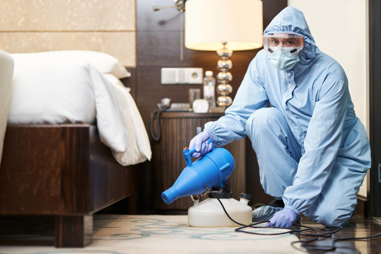 NexHive Pest Control technician in protective suit treating a bedroom in West Palm Beach