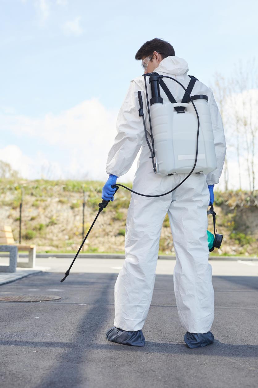 NexHive pest control technician with backpack sprayer treating outdoor area